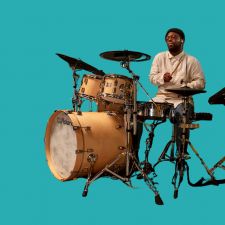 Man playing a hybrid electronic and standard drum kit.